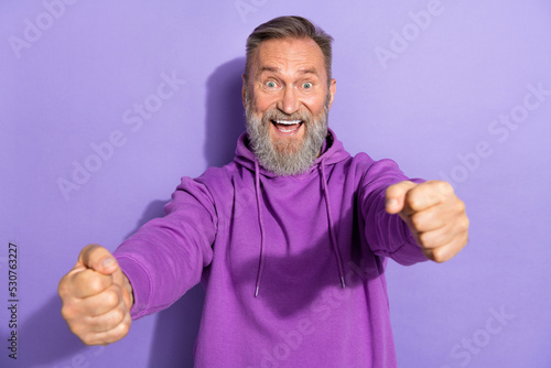 Photo of handsome retired impressed ecstatic man white gray beard purple hoodie imagine he in vehicle isolated on violet color background