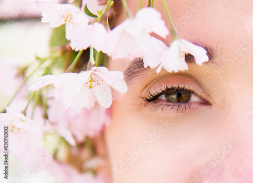 close up portrait of a smiling blonde woman in spring park in pink blossoming sakura 