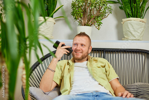 Quadro su tela Happy smiling man holding mobile phone speaking talking with friends or family u