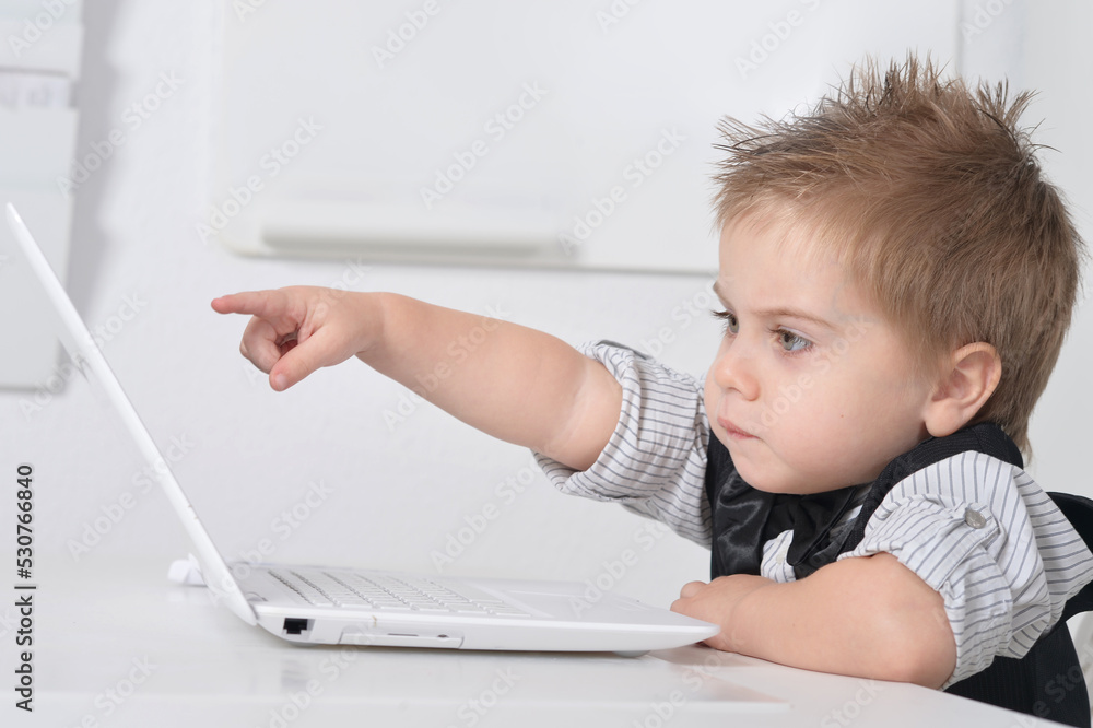 Little handsome boy sits with a computer Little handsome boy sits with a computer