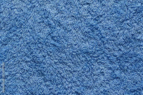 An extreme close-up of a blue fluffy, shaggy, bathroom towel, flat, vertical and parallel to camera