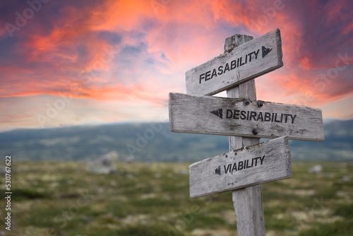feasability desirability viability text quote on wooden signpost up on the mountains during sunset and red dramatic skies. photo