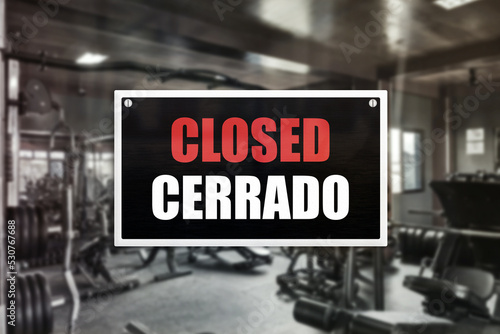 A closed sign with spanish translation in front of a gym.