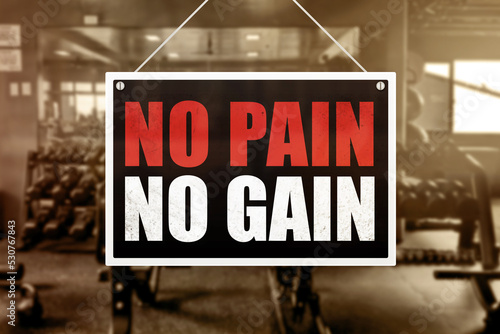 No Pain No Gain Sign in front of a gym background. Motivation or encouragement concept.