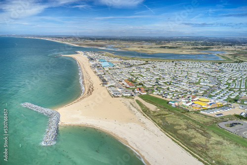 Aerial photo over West Sands at Selsey in West Sussex with a large holiday caravans park next to the beach and Medmerry nature reserve in the background.