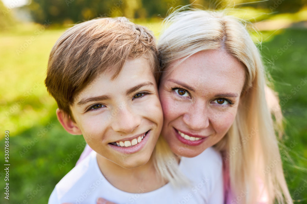 Glückliche Mutter und lächelnder Sohn im Garten Glückliche Mutter und lächelnder Sohn im Garten
