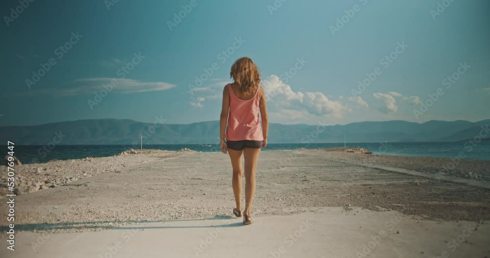 Woman walking on a concrete jetty towards to the sea water. Woman walking on a concrete jetty towards to the sea water.