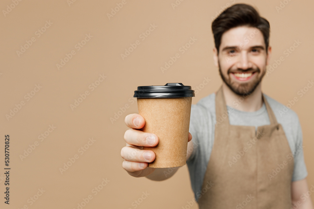 Young smiling fun man barista barman employee wear brown apron work in shop  hold give craft