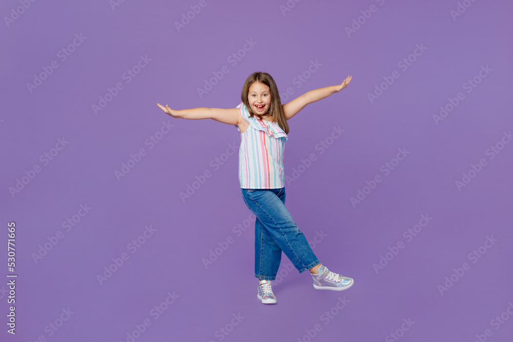 Full body little kid child girl 5-6 year old wear casual clothes stand with outstretched hands raise up leg isolated on plain pastel light purple background Mother's Day love family lifestyle concept