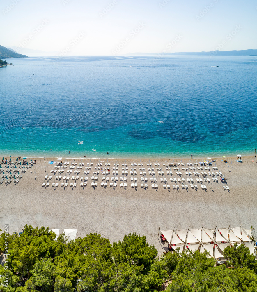 Aerial view of sunbeds lined up on beach on Zlatni Rat in Bol on the island of Brac, Croatia. Aerial view of sunbeds lined up on beach on Zlatni Rat in Bol on the island of Brac, Croatia.