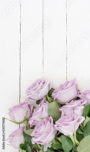 a bouquet of beautiful purple roses on a white wooden background top view with a copy of the space