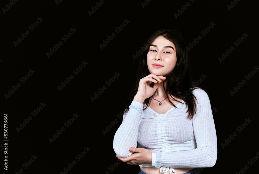Beautiful young woman in white blouse resting her chin on her hand while looking at camera with satisfied emotion on her face on black background. Banner with copy space. Natural beauty, Clean skin. Beautiful young woman in white blouse resting her chin on her hand while looking at camera with satisfied emotion on her face on black background. Banner with copy space. Natural beauty, Clean skin.