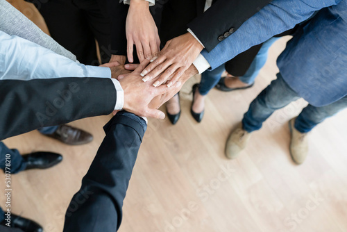 Unrecognizable business people holding hands standing in modern office, above view, teamwork concept