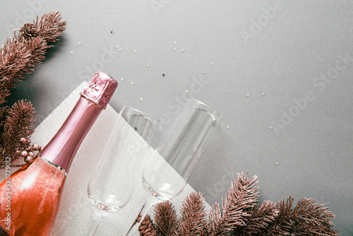 Obraz na plátně A bottle of champagne, glasses, rose gold Christmas tree branches on a light gray background