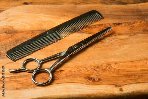 Simple plastic comb and metal scissors. Man grooming accessories on a wooden board,. Hair and beard styling. Still life.