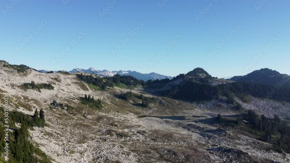 Aerial View of Mount Brew Showing Rocky Landscape and Pine Trees Panning to Reveal Sun Relfecting Lake and Hazy Mountain Terrain in Canada BC 4K Aerial View of Mount Brew Showing Rocky Landscape and Pine Trees Panning to Reveal Sun Relfecting Lake and Hazy Mountain Terrain in Canada BC 4K