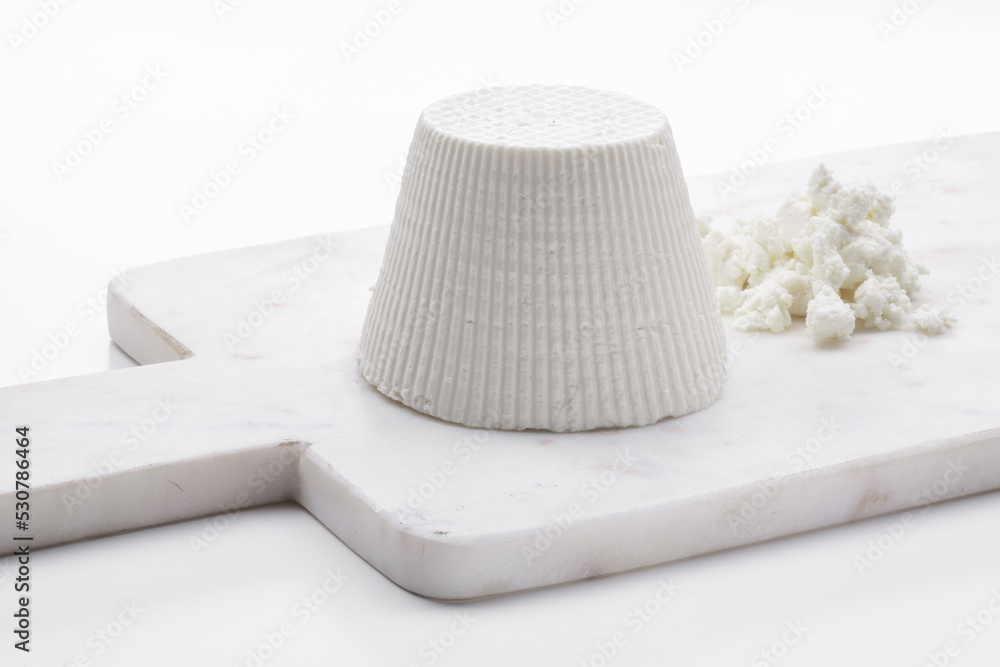 whole ricotta cheese on a white marble cutting board whole ricotta cheese on a white marble cutting board