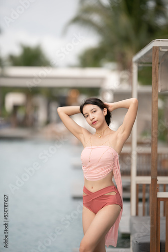 Woman in sexy bikini at poolside outdoor.