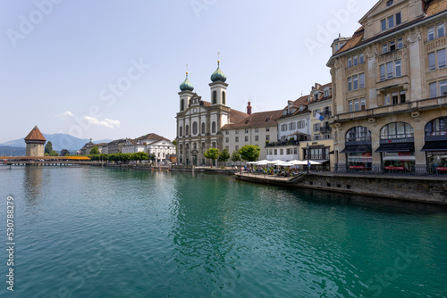 LUCERNE, SWITZERLAND, JUNE 21, 2022 - View of the Jesuit church of St. Franz Xaver and the Kapellbrücke Bridge on the background on the Reuss river in Lucerne, Switzerland