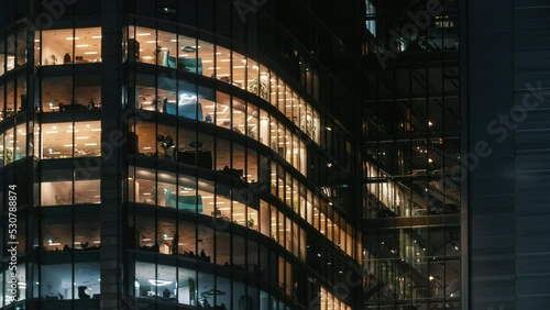 Time lapse blinking office windows lights in business center building facade, people working late night. Corporate business, high skyscraper glass surface. Light in building windows turn on and off photo