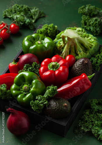 assorted red and green vegetables tomatoes, bell peppers, kale avocado