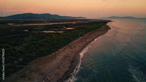 Tuscany seaside Cinemagraph seamless video loop in Italy by sunset in nature. Bird view aerial drone flight above a natural tourist vacation sea coast sand beach sandy bay with clear blue water in 4K.
