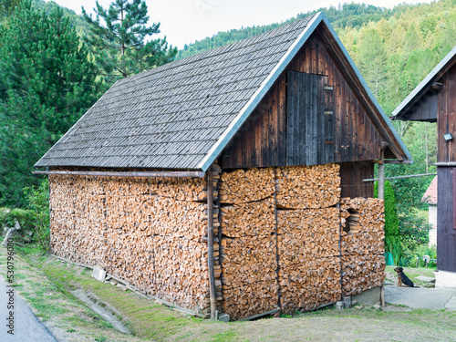 Huge woodshed in the mountains filled with pieces of chopped firewood - airy, with a storage room under a sloping roof on both sides