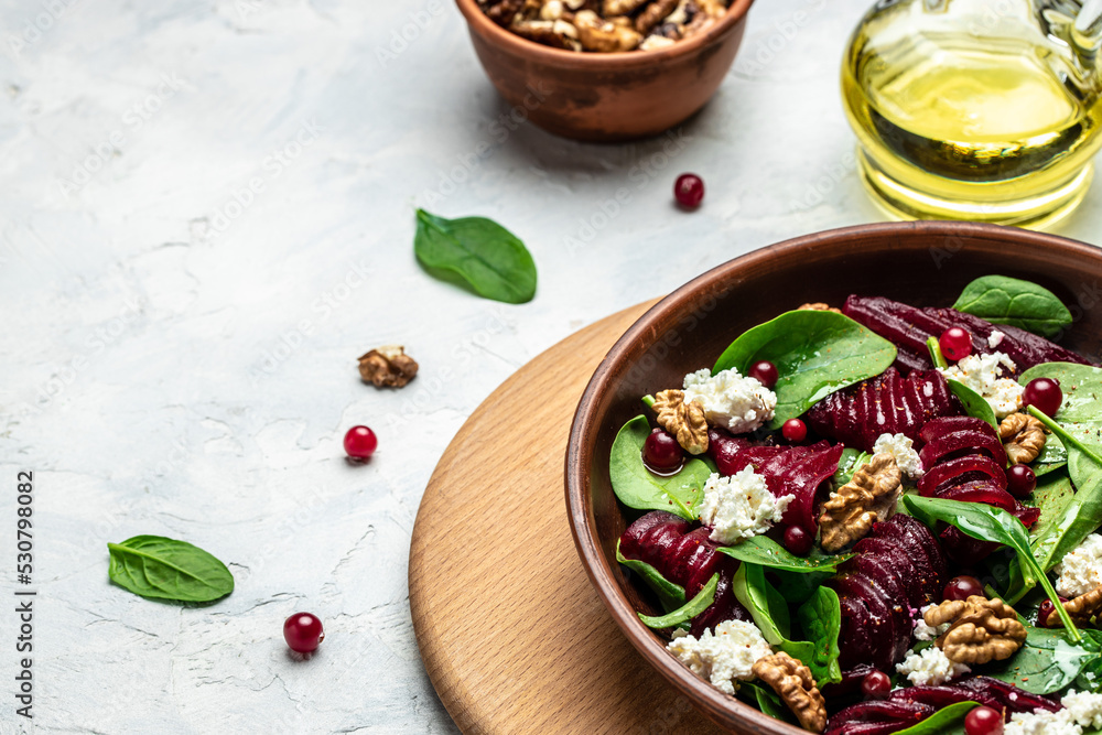 Healthy Beet Salad with fresh sweet baby spinach, cheese, nuts, cranberries on a dark background. place for text, top view