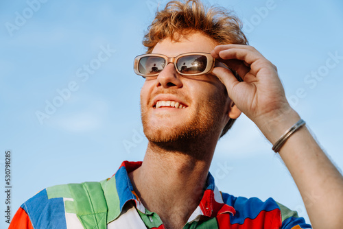 Cuadro en lienzo Young handsome stylish smiling man adjusting his sun glasses