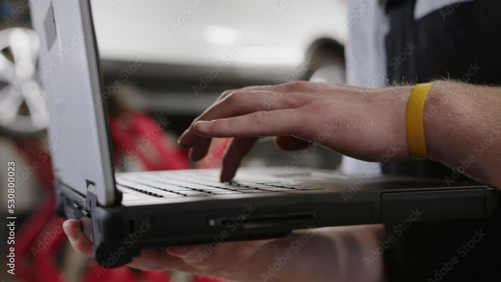 Close-up of the hands of an auto electrician who presses the keys of a diagnostic laptop Close-up of the hands of an auto electrician who presses the keys of a diagnostic laptop