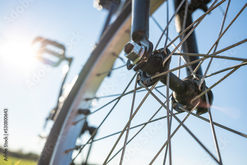 Close-up detail of a bicycle parked in a meadow  against the backdrop of the sun and blue sky. Active lifestyle concept. Bottom view.