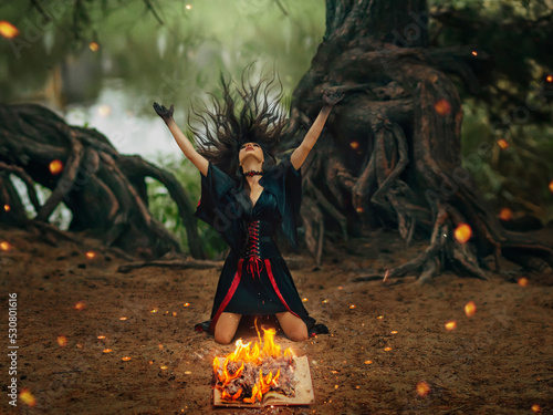 Canvas Print Fantasy female pagan witch creating magic casts spell dancing ritual dance near burning hearth of fire, waves head arms hands raised to sky, long black hair flying in wind motion