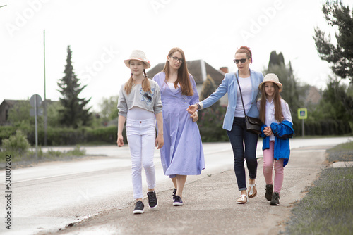  Two females mothers sisters business women going for a walk with a children girls in summer sun hat