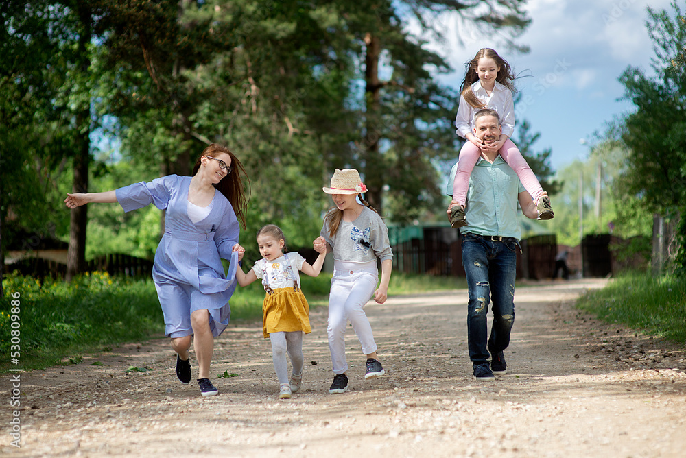 Fototapeta premium Happy family- mother,father and three children daughter little girls having fun on village road