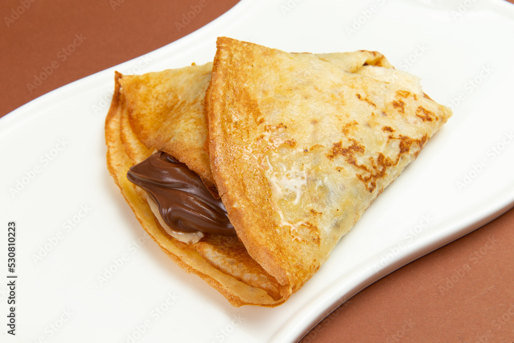 Pancakes with chocolate paste and banana in a plate. Pancakes with chocolate paste and banana in a plate.