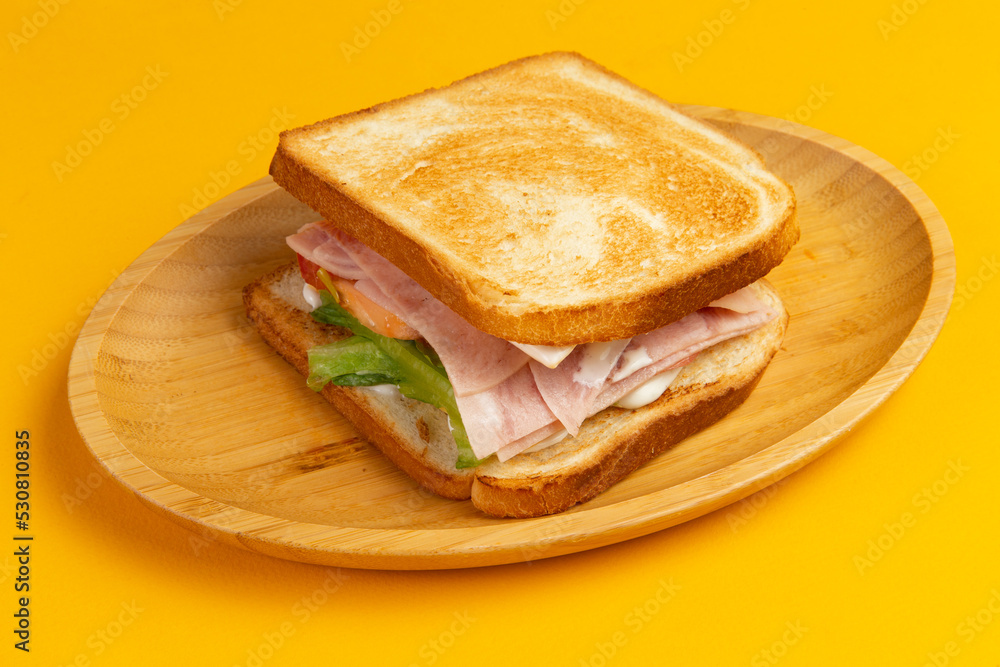 Sandwich with ham and salad in a wooden plate. Sandwich with ham and salad in a wooden plate.