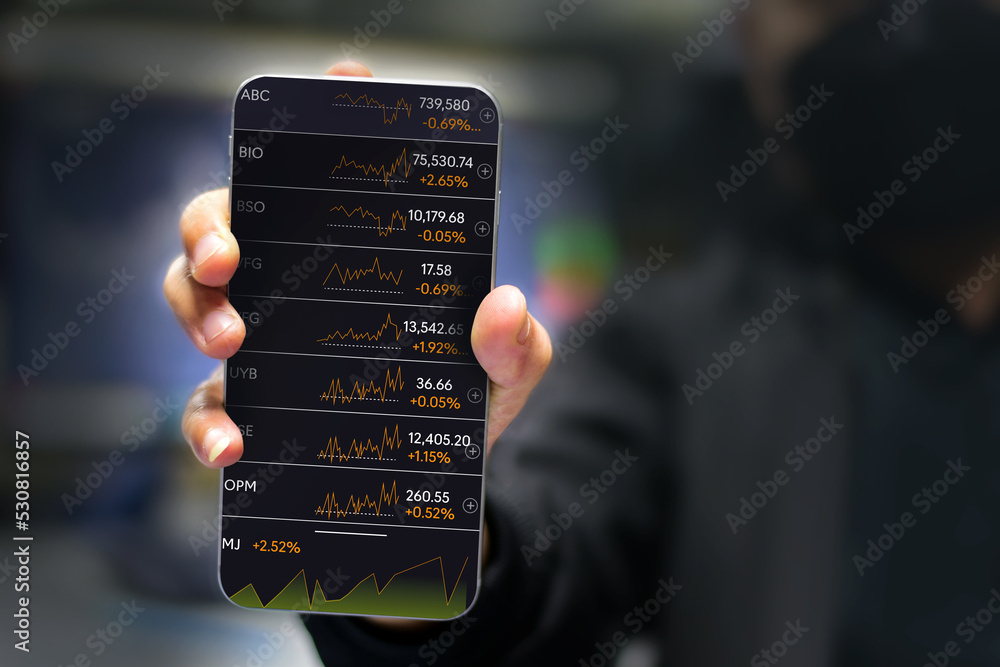 Obraz premium Hands of a businessman working with a smartphone Technical price charts and indicators and mobile screen background for stock trading