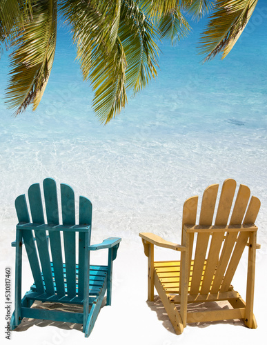 Beach chairs under palm branch in Aruba.. Soft wave of turquoise ocean water