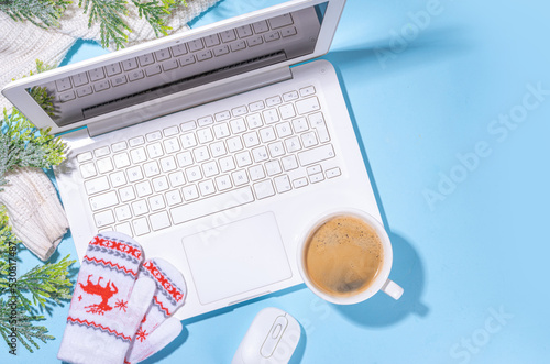 Winter and Christmas office workspace background with laptop, notepad, knitted mittens, sweater or plaid, Christmas tree branches, gift box, decoration on workplace flatlay top view copy space © ricka_kinamoto