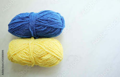 Yellow and blue yarn balls on light background 