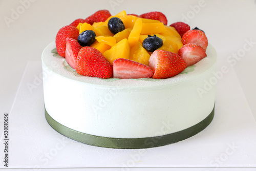 Deliciously creamy birthday cake, fruit cake, filled with fresh strawberries, blueberries and mango