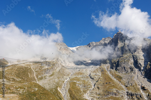 Mountain Range of the Italian Alps on a Sunny Summer Day, close-up view of the Rocks and Blue Sky with Clouds