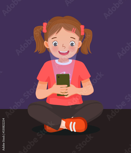 cute little girl playing game with smart phone at night with blue light reflection harmful to eyes 