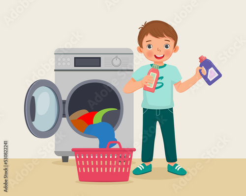 happy little boy holding detergent and fabric softener doing laundry daily chores with washing machine 