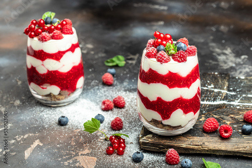 Raspberry dessert cheesecake, trifle, mouse in a glass. Raspberry Greek yogurt granola parfait on a dark background. Restaurant menu, dieting, cookbook recipe