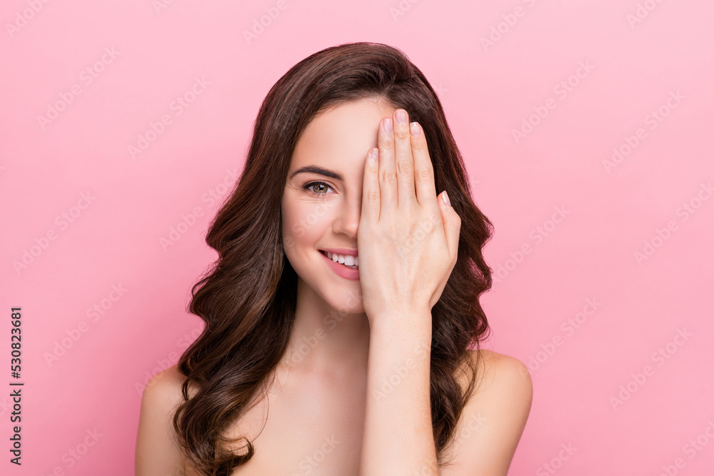 Photo of young cheerful woman cover hand eye plastic surgery collagen isolated over pink color background Photo of young cheerful woman cover hand eye plastic surgery collagen isolated over pink color background