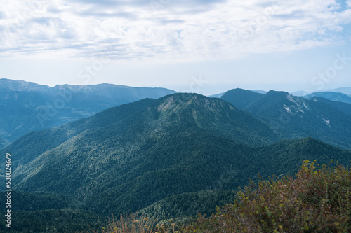 Alpine Meadows Trail  Krasnaya Polyana Resort. Alpine Meadows Walking Route. Aerial view of the green mountain valley  surrounded by high mountains.