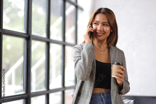 Attractive and sexy young businesswoman in office uses mobile phone to call with colleagues and business partners. © Wasan