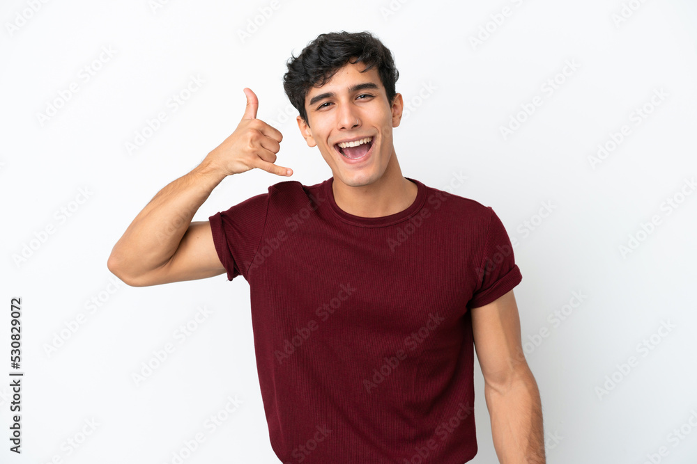 Young Argentinian man isolated on white background making phone gesture. Call me back sign Young Argentinian man isolated on white background making phone gesture. Call me back sign