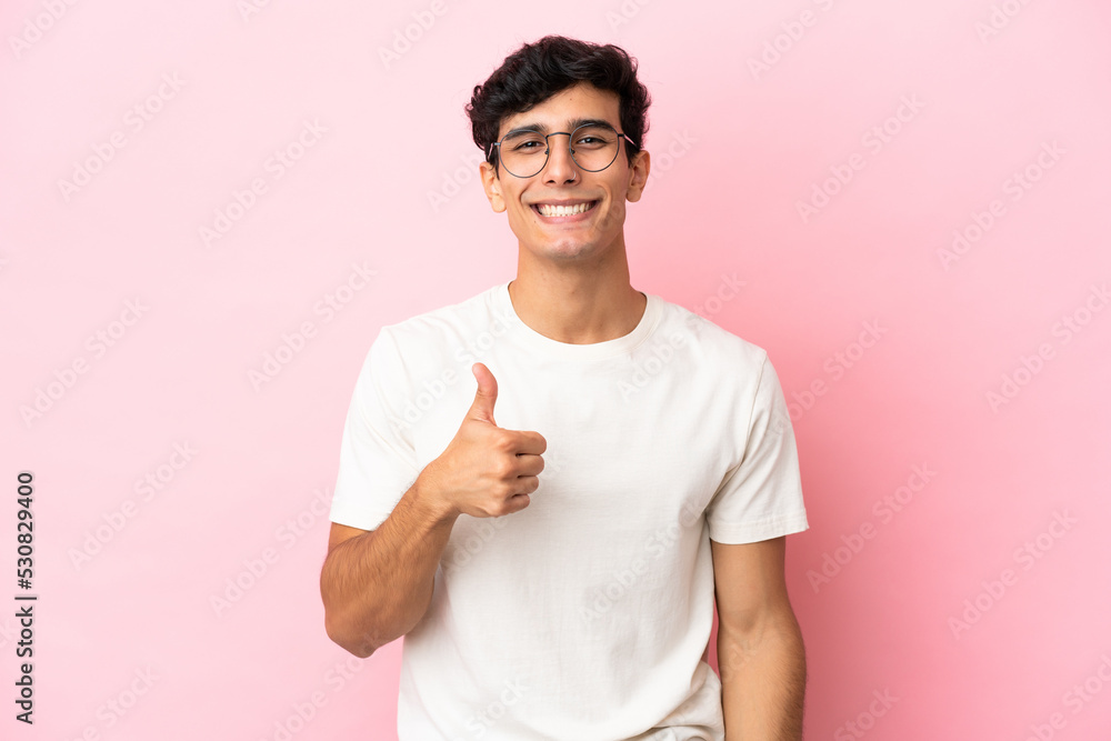 Young Argentinian man isolated on pink background giving a thumbs up gesture Young Argentinian man isolated on pink background giving a thumbs up gesture
